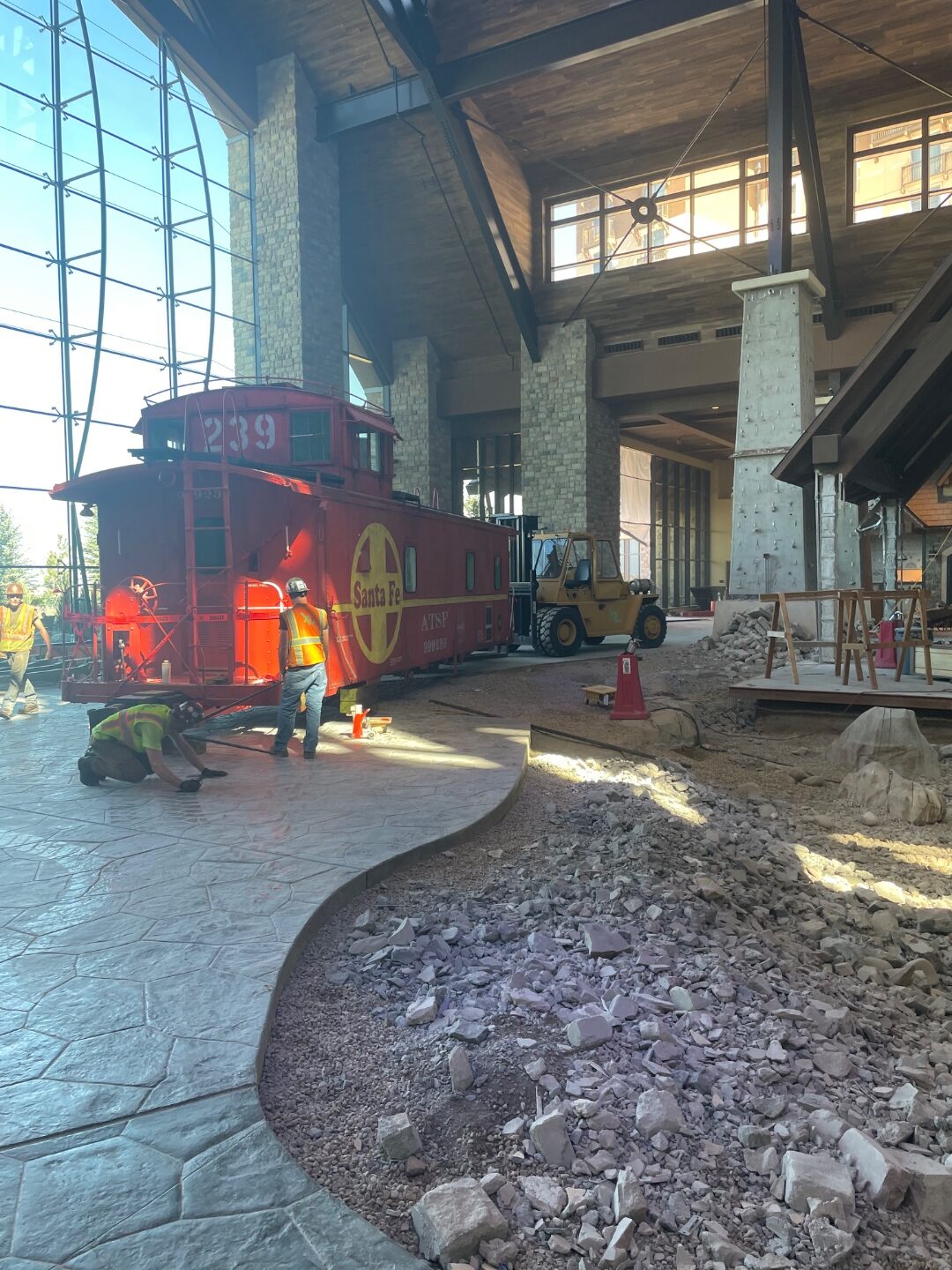 Forklift positioning an antique caboose inside a lobby